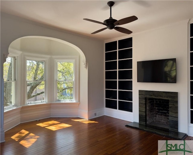 unfurnished living room featuring hardwood / wood-style flooring, built in features, and ornamental molding