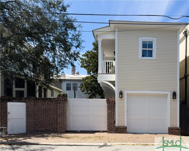 view of front of home with a balcony, an attached garage, and fence