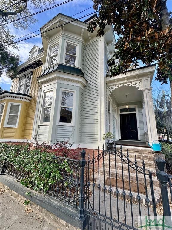 italianate home featuring a porch, a gate, and a fenced front yard