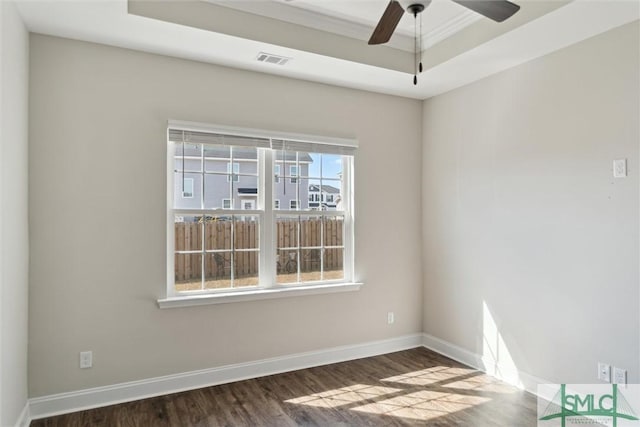 empty room featuring baseboards, visible vents, a ceiling fan, wood finished floors, and a tray ceiling