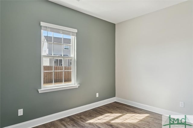 spare room featuring baseboards and wood finished floors