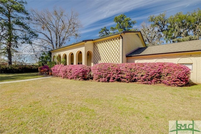 view of property exterior with an attached garage, a lawn, and brick siding