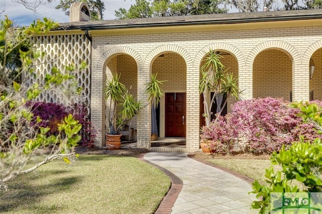 doorway to property with a chimney and brick siding