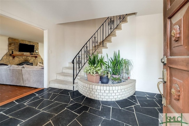 entryway featuring stairs and a stone fireplace