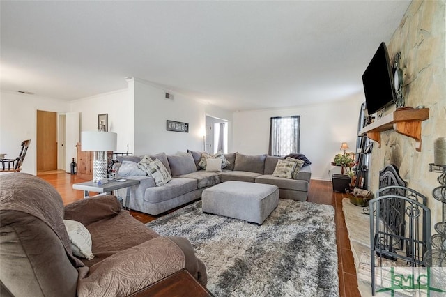 living area with a fireplace, visible vents, and wood finished floors