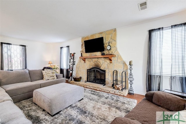 living area with a healthy amount of sunlight, a fireplace, visible vents, and wood finished floors