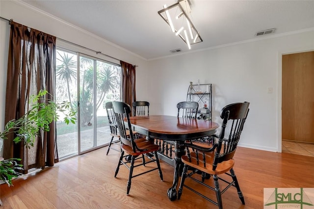 dining area featuring light wood-style floors, visible vents, and crown molding