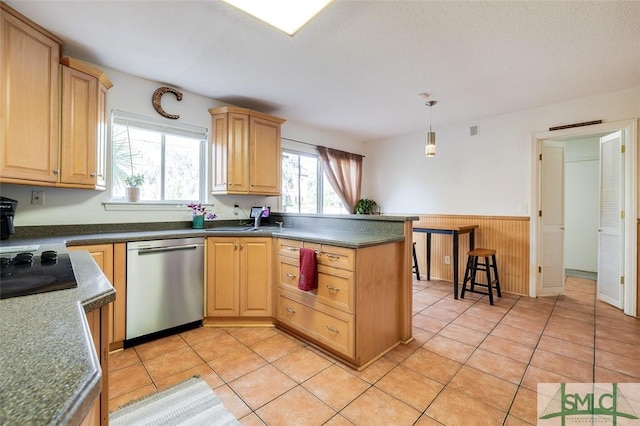 kitchen with light tile patterned floors, light brown cabinets, a wainscoted wall, a peninsula, and stainless steel dishwasher