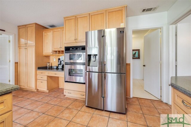 kitchen with light tile patterned flooring, light brown cabinets, visible vents, appliances with stainless steel finishes, and dark countertops