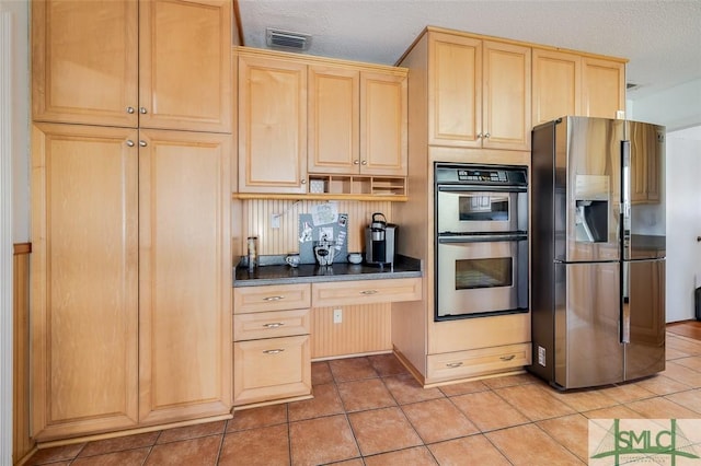 kitchen with light tile patterned flooring, light brown cabinets, visible vents, appliances with stainless steel finishes, and dark countertops