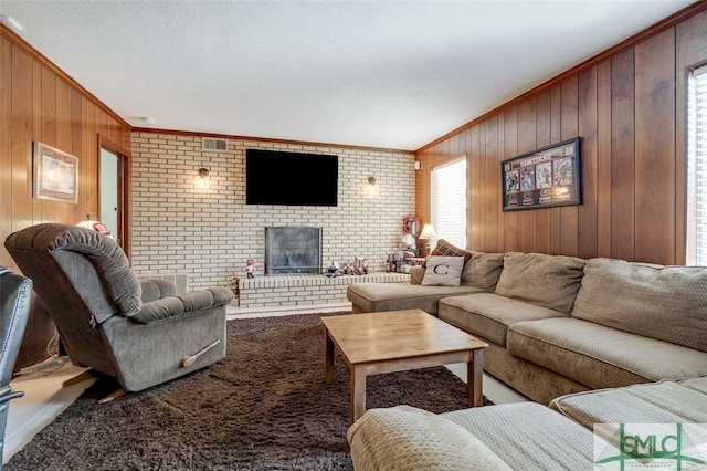 living area with a brick fireplace, visible vents, crown molding, and wooden walls