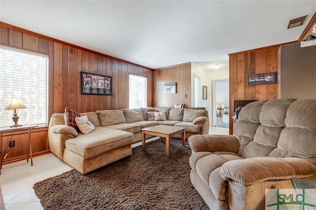 living room with wood walls, a textured ceiling, ornamental molding, and a wealth of natural light