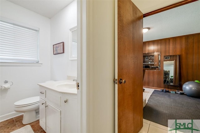 bathroom with wooden walls, vanity, toilet, and tile patterned floors