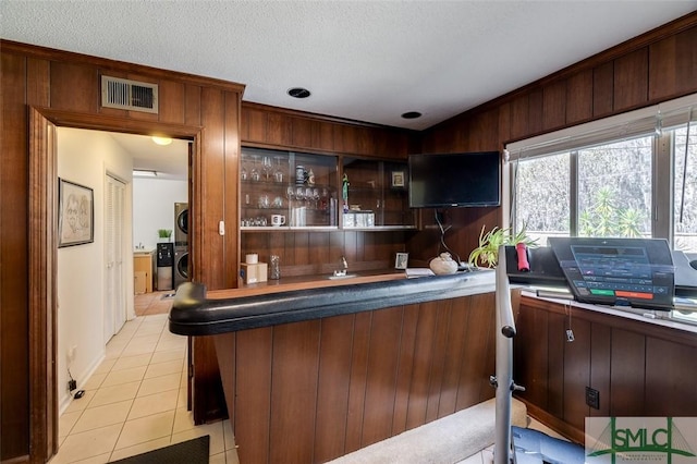 bar featuring a textured ceiling, light tile patterned flooring, visible vents, washer and dryer, and wet bar