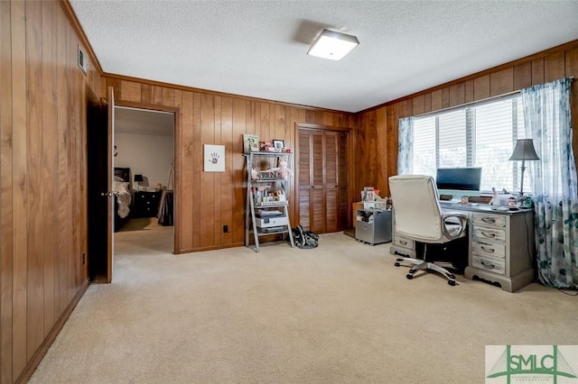 office space with crown molding, wooden walls, a textured ceiling, and light colored carpet