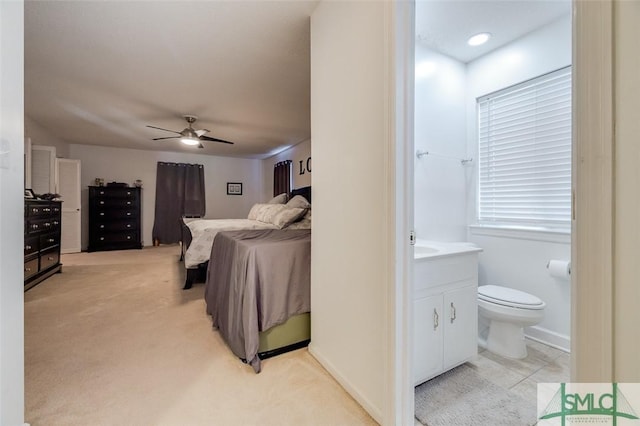 bedroom featuring light carpet, a ceiling fan, and ensuite bathroom