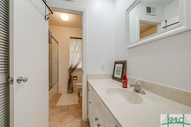 bathroom featuring a shower with door, visible vents, toilet, vanity, and tile patterned flooring