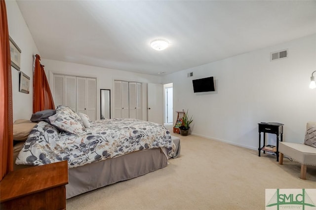 bedroom with baseboards, carpet flooring, visible vents, and multiple closets