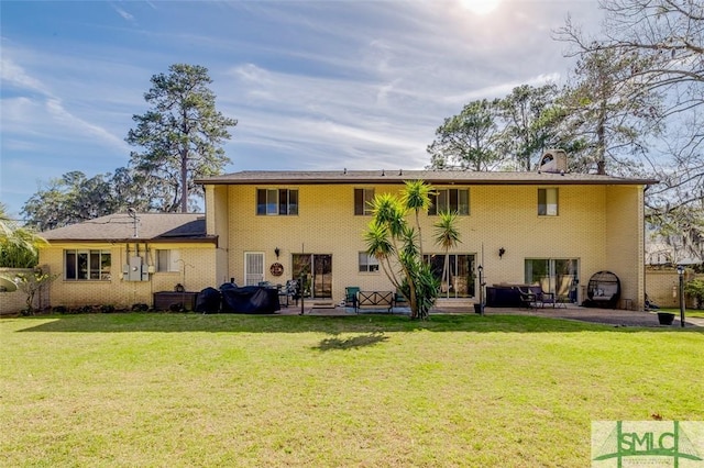 back of house featuring a yard, brick siding, and a patio area