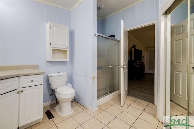 bathroom featuring a stall shower, tile patterned flooring, toilet, and crown molding