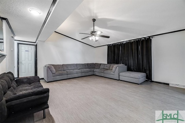 living area with baseboards, ceiling fan, visible vents, and a textured ceiling