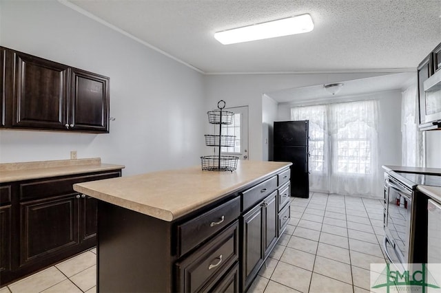 kitchen featuring lofted ceiling, light tile patterned floors, freestanding refrigerator, and stainless steel electric stove