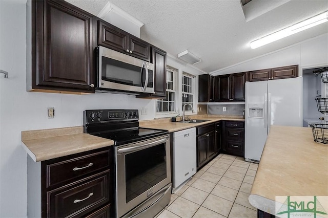 kitchen with appliances with stainless steel finishes, vaulted ceiling, light countertops, and a sink