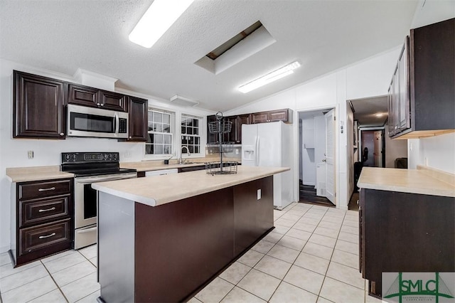 kitchen with lofted ceiling, light tile patterned floors, a sink, light countertops, and appliances with stainless steel finishes