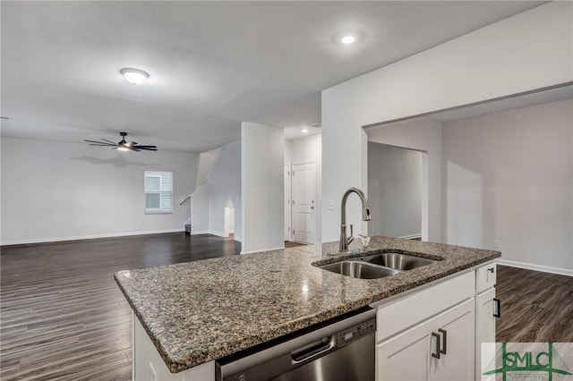 kitchen featuring dark wood-style flooring, dark stone counters, a sink, dishwasher, and an island with sink