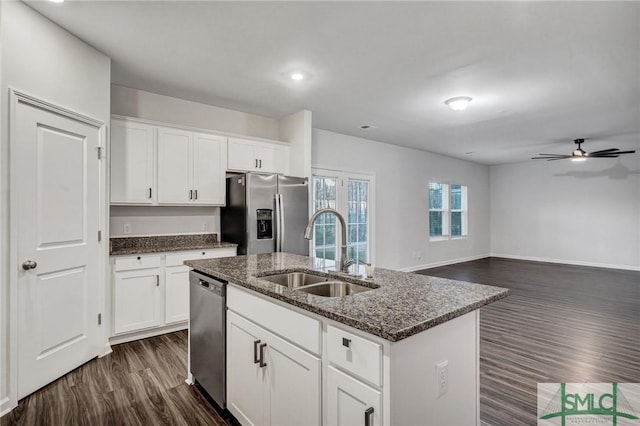 kitchen featuring a center island with sink, dark stone countertops, dark wood-style flooring, stainless steel appliances, and a sink