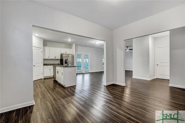 unfurnished living room featuring baseboards and dark wood finished floors