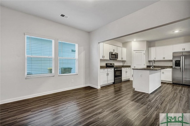 kitchen featuring white cabinetry, baseboards, appliances with stainless steel finishes, dark wood-style floors, and dark countertops