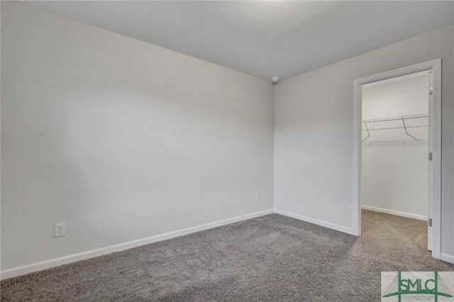 unfurnished bedroom with carpet floors, a spacious closet, baseboards, and a closet