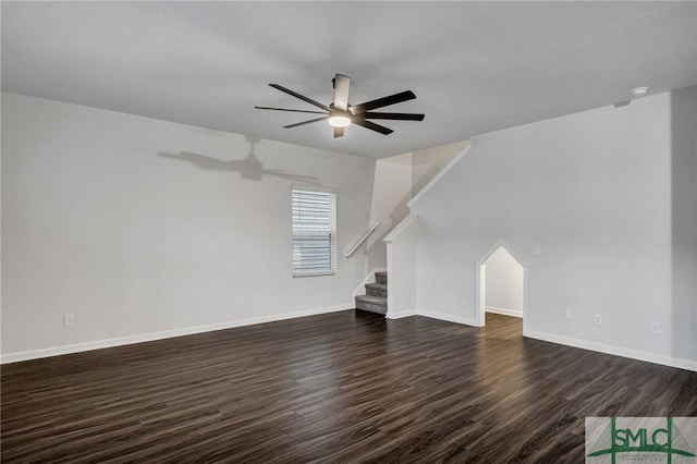 unfurnished living room featuring a ceiling fan, baseboards, stairway, and dark wood-style flooring