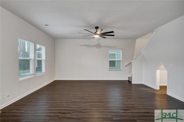 unfurnished living room with stairs, ceiling fan, dark wood-type flooring, and baseboards