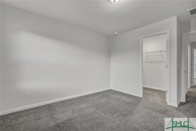 unfurnished bedroom featuring carpet floors, a walk in closet, a closet, and baseboards