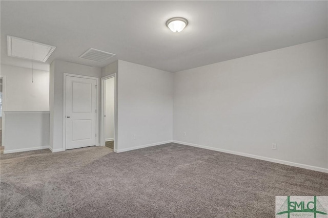 carpeted spare room with attic access, visible vents, and baseboards