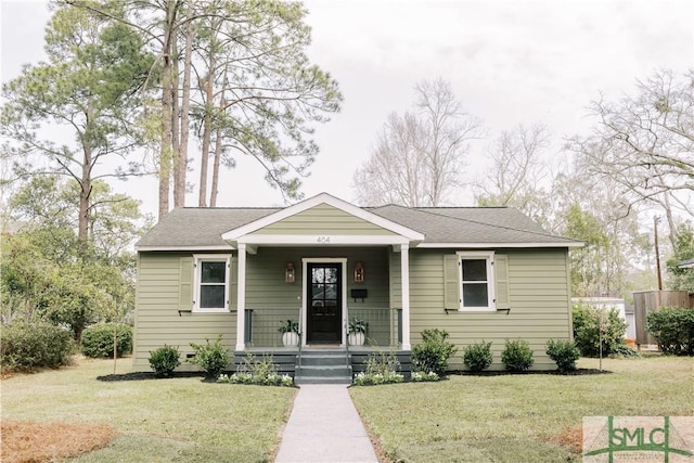 bungalow-style home with covered porch, roof with shingles, and a front yard