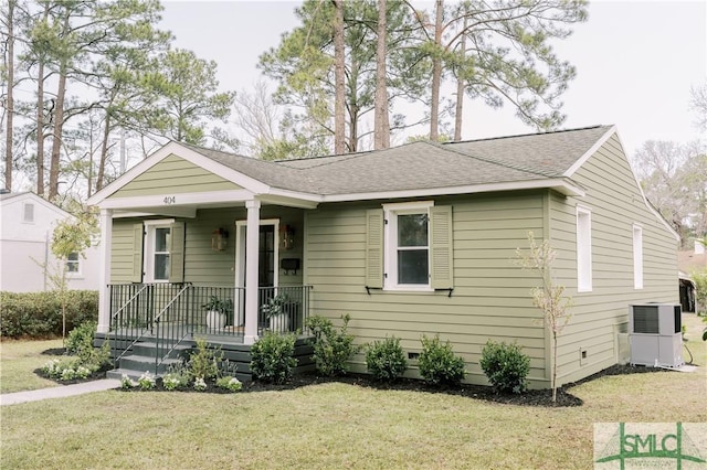 view of front facade with roof with shingles, crawl space, a porch, central AC, and a front yard