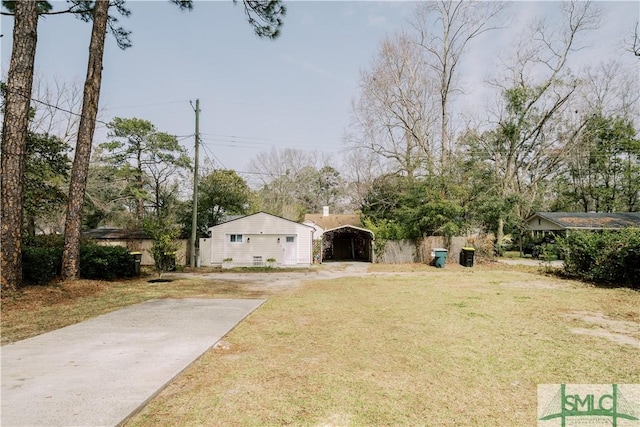 view of yard featuring a carport, an outbuilding, and concrete driveway