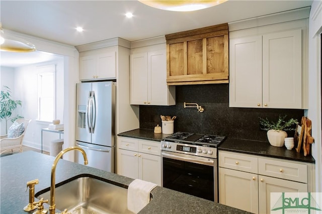 kitchen with a sink, white cabinetry, appliances with stainless steel finishes, tasteful backsplash, and dark stone countertops