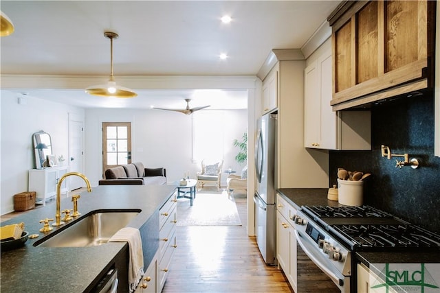 kitchen featuring open floor plan, stainless steel appliances, light wood-style floors, white cabinetry, and a sink