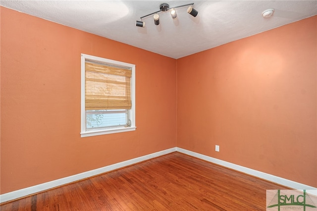 spare room with wood finished floors and baseboards