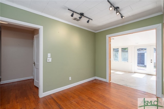 empty room featuring baseboards, crown molding, visible vents, and wood finished floors