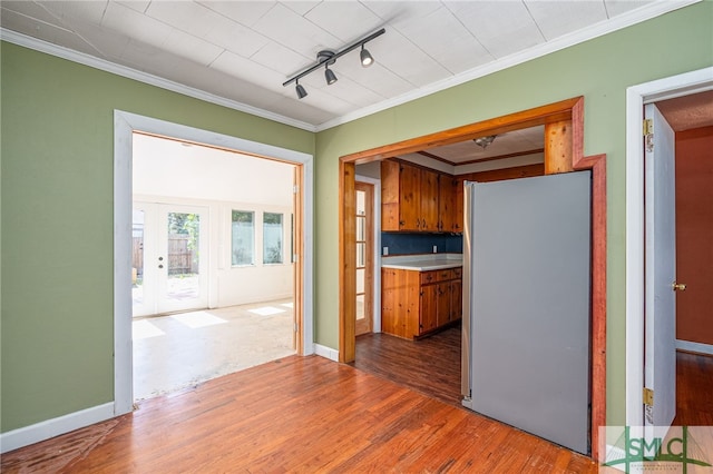 interior space featuring baseboards, french doors, wood finished floors, and crown molding