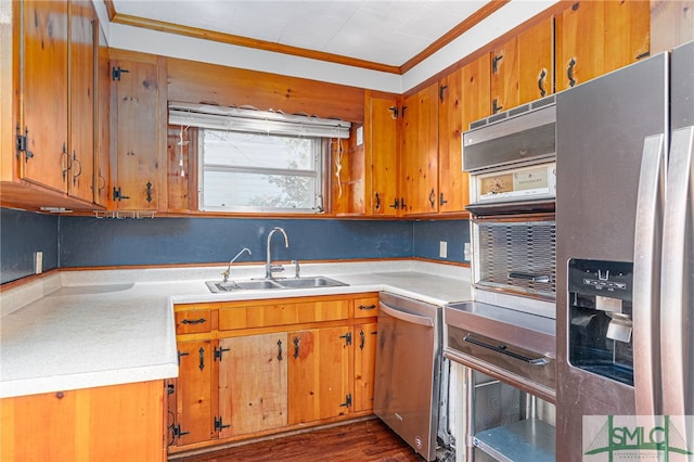 kitchen featuring brown cabinets, stainless steel appliances, crown molding, light countertops, and a sink