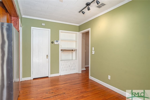 unfurnished bedroom featuring crown molding, visible vents, wood finished floors, and freestanding refrigerator