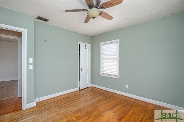 spare room featuring visible vents, ceiling fan, baseboards, and wood finished floors