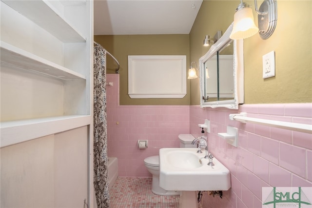 full bath featuring toilet, a wainscoted wall, a sink, tile patterned flooring, and tile walls