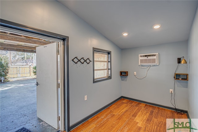 clothes washing area with a healthy amount of sunlight, light wood-style flooring, baseboards, and an AC wall unit